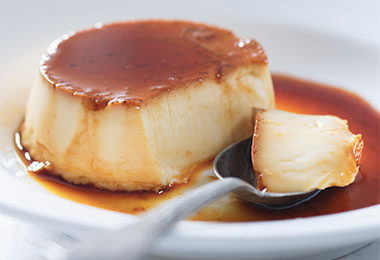 Plato y cuchara con flan casero cubierto de caramelo